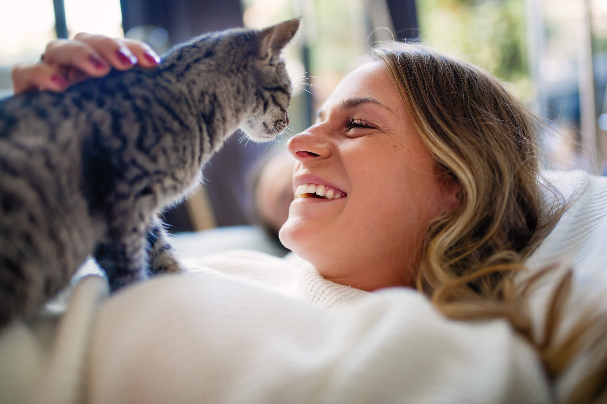 A happy pet owner smiles are her kitten