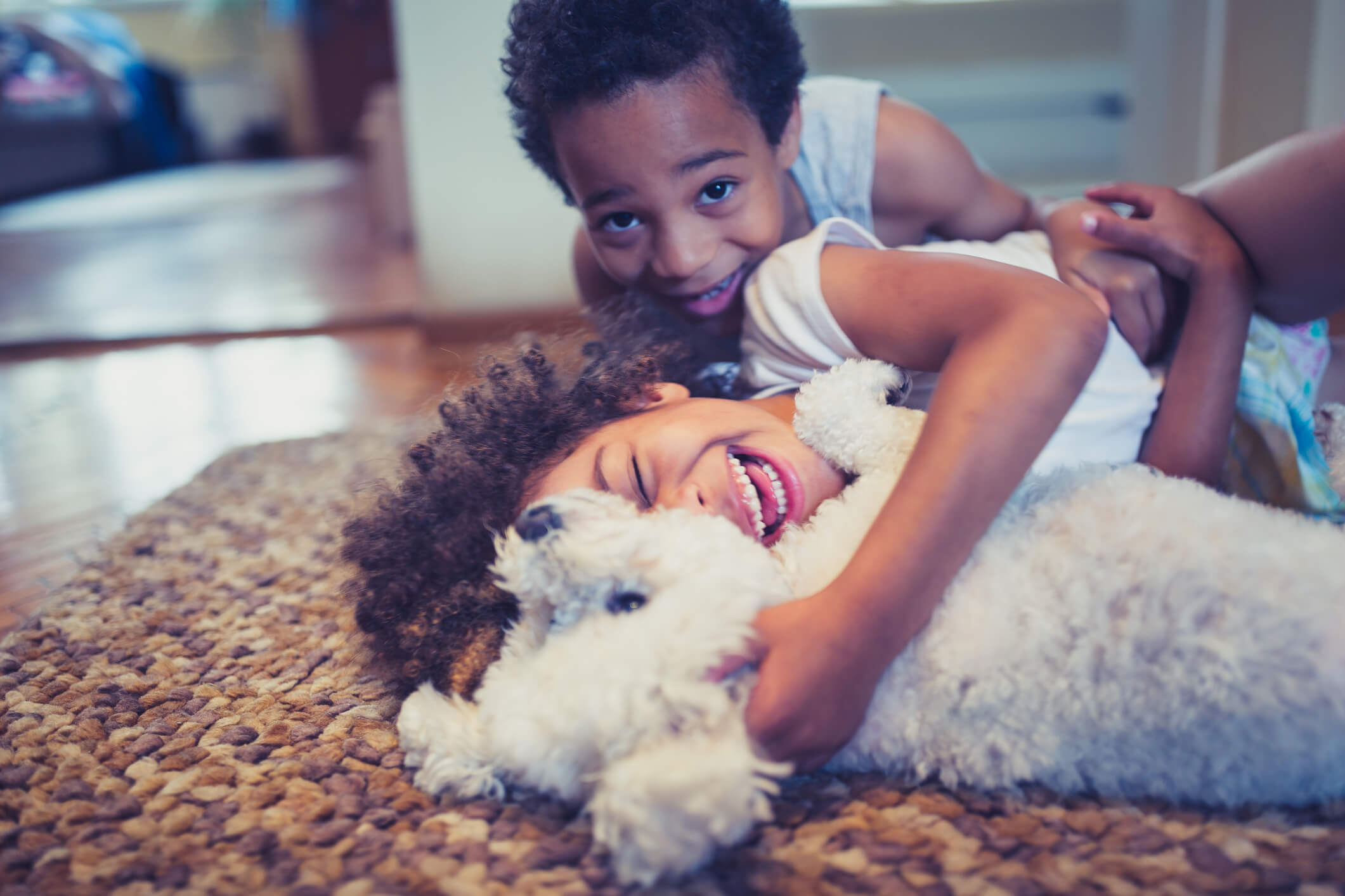 Two small children play with their puppy on the floor