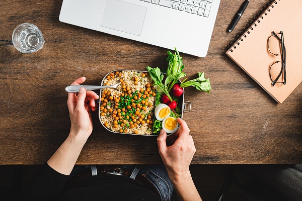 Point of view of a woman sitting on a workdesk eating healthy lunch. Female having healthy lunch break at work.