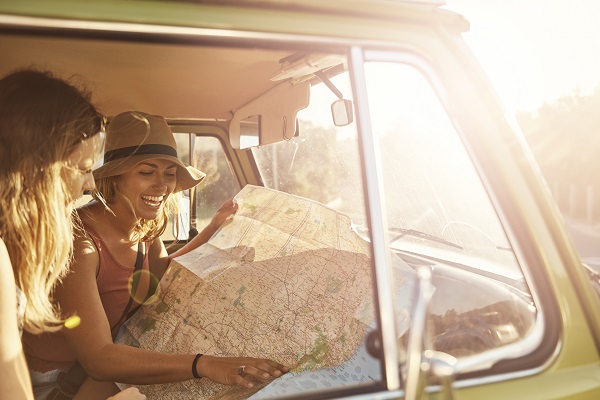 Shot of two friends looking at a map while out on a roadtrip