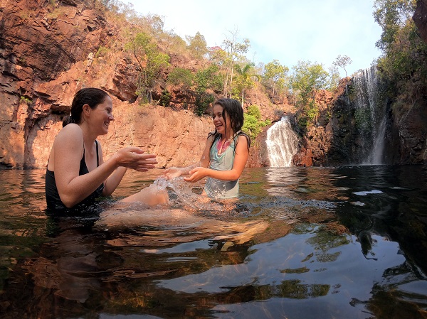 A mother and daughter swim at the base of a waterfall