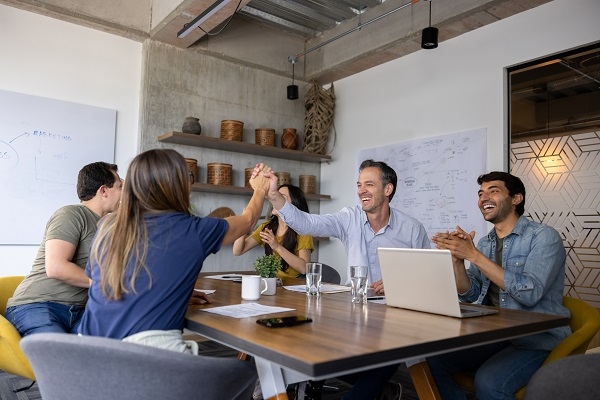 Group of people closing a deal in a successful business meeting at the office and celebrating with a high-five