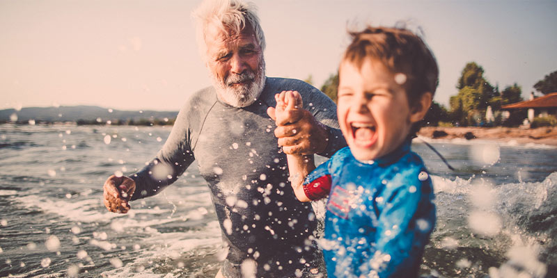 A grandfather and grandson going for a surf 