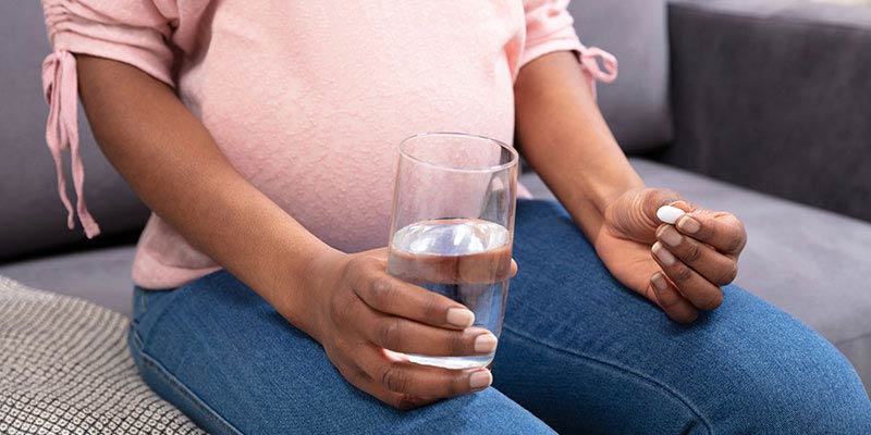 A woman holding a glass of water and a tablet A woman holding a glass of water and a tablet