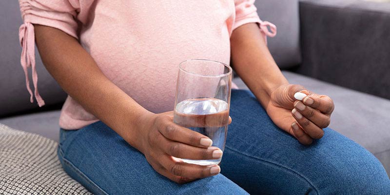 A woman holding a glass of water and a tablet