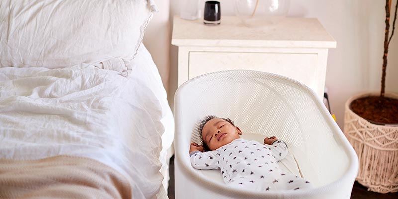 A baby sleeping in its bassinet