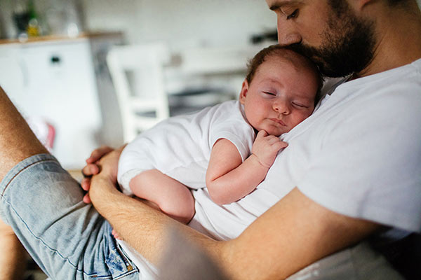 A dad cuddling his newborn baby