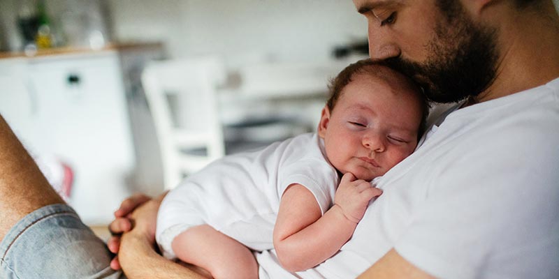 father cuddling newborn baby