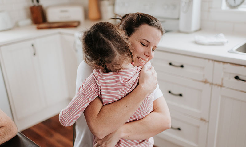 mum hugging young daughter in the kitchen