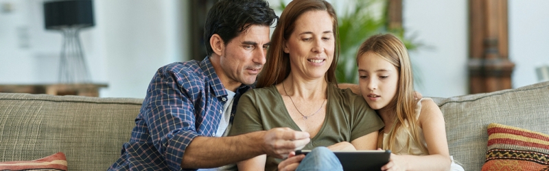 A family picture with father, mother and daughter checking a tablet