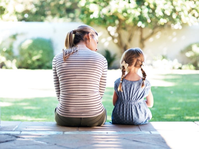 mother talking to young daughter on step