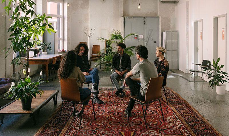 group of 5 people sitting in a circle in a group therapy session