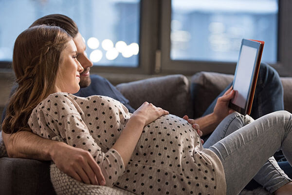 Young pregnant couple looking at ipad