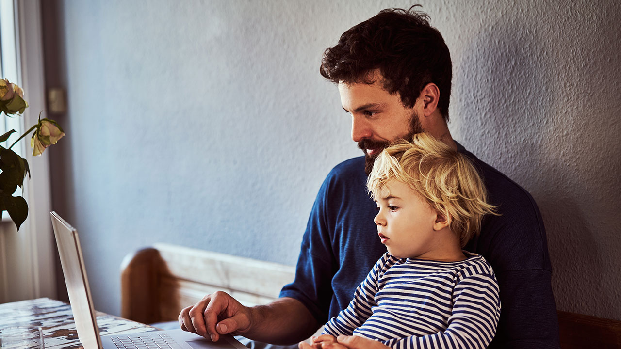 father with young child looking at a laptop