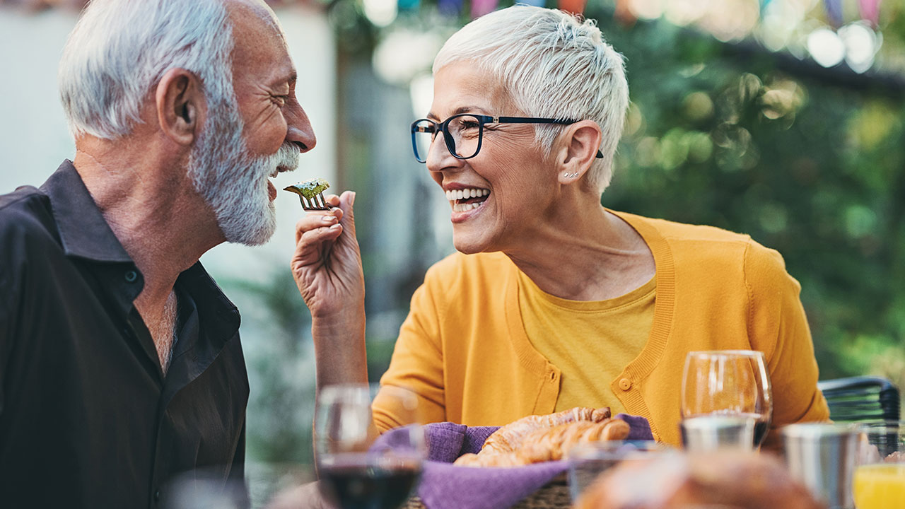 woman playfully feeding man with spoon at lunch