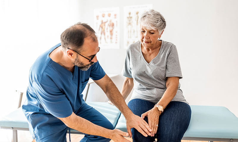 woman being treated for knee pain by a practitioner woman being treated for knee pain by a practitioner