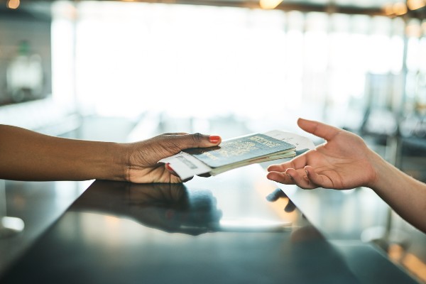 An overseas student passing their passport over a counter