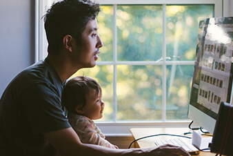 Dad using computer with his son in his lap