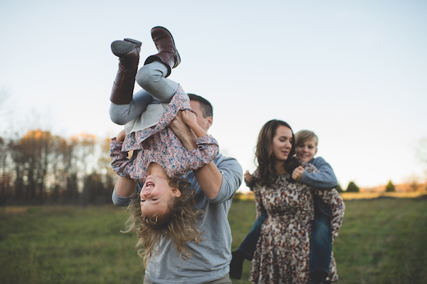Young couple carrying son and daughter in field Young couple carrying son and daughter in field
