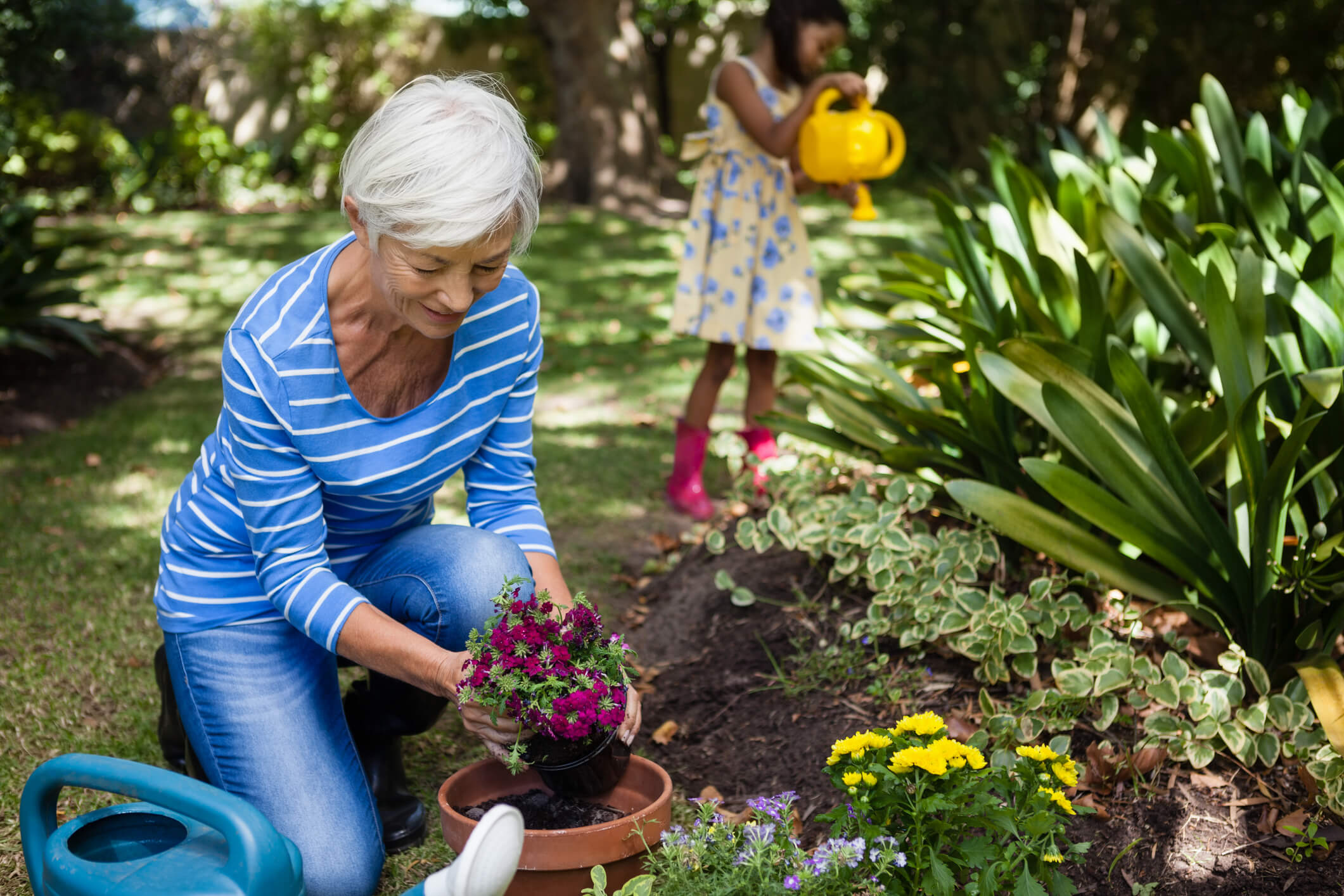 older female lady bending down to plant a pot and be active to avoid knee replacement surgery 
