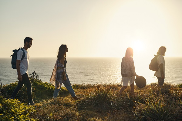 A group of four friends hike along a coastal cliff