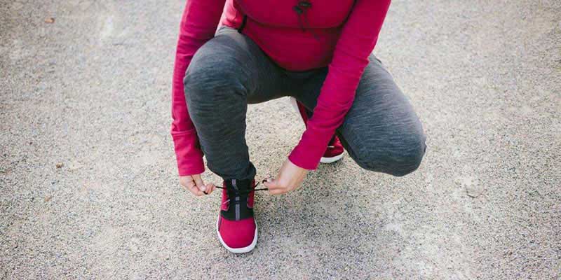A woman putting on her sneakers